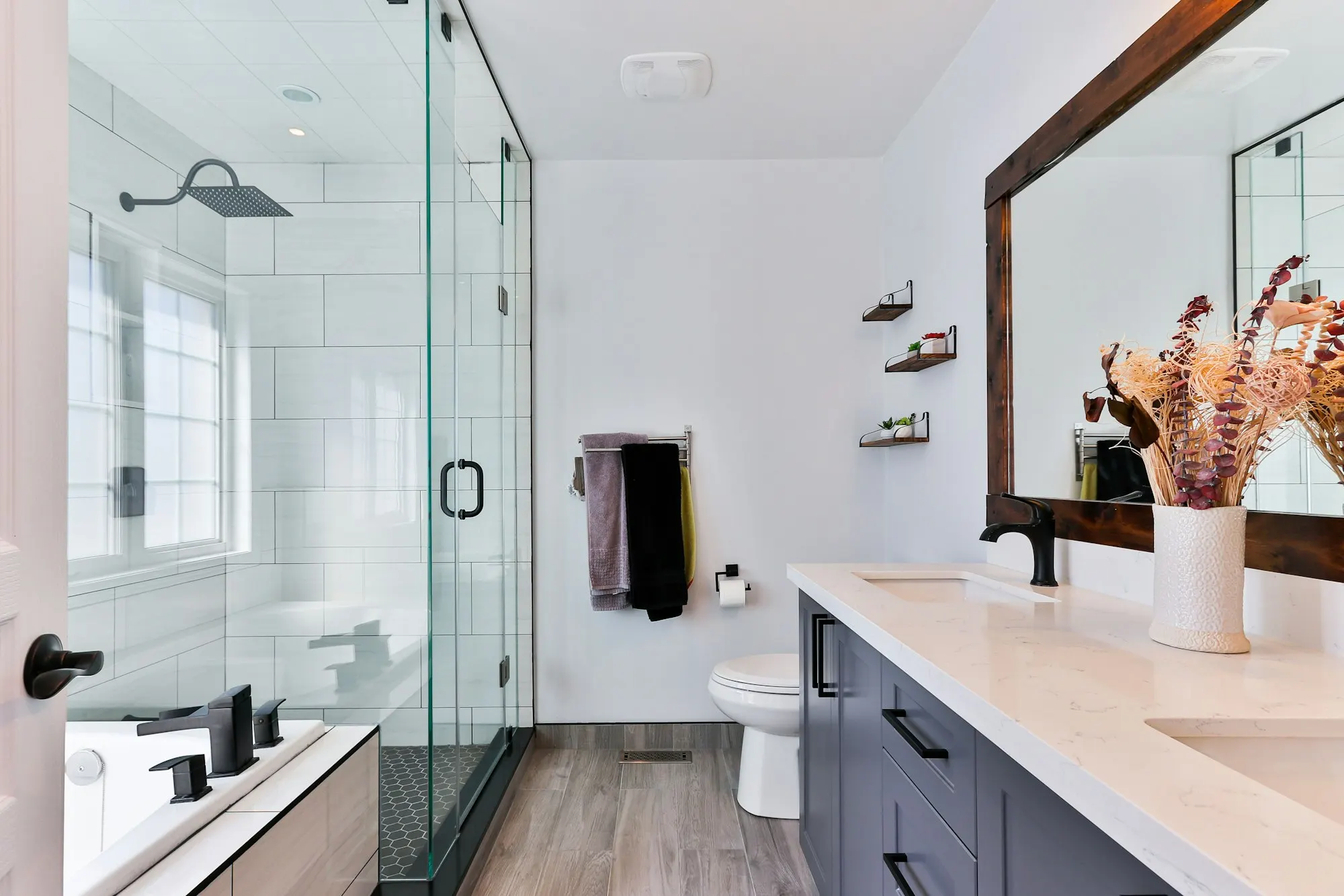 Bathroom with a frameless glass shower, dark vanity and white tile