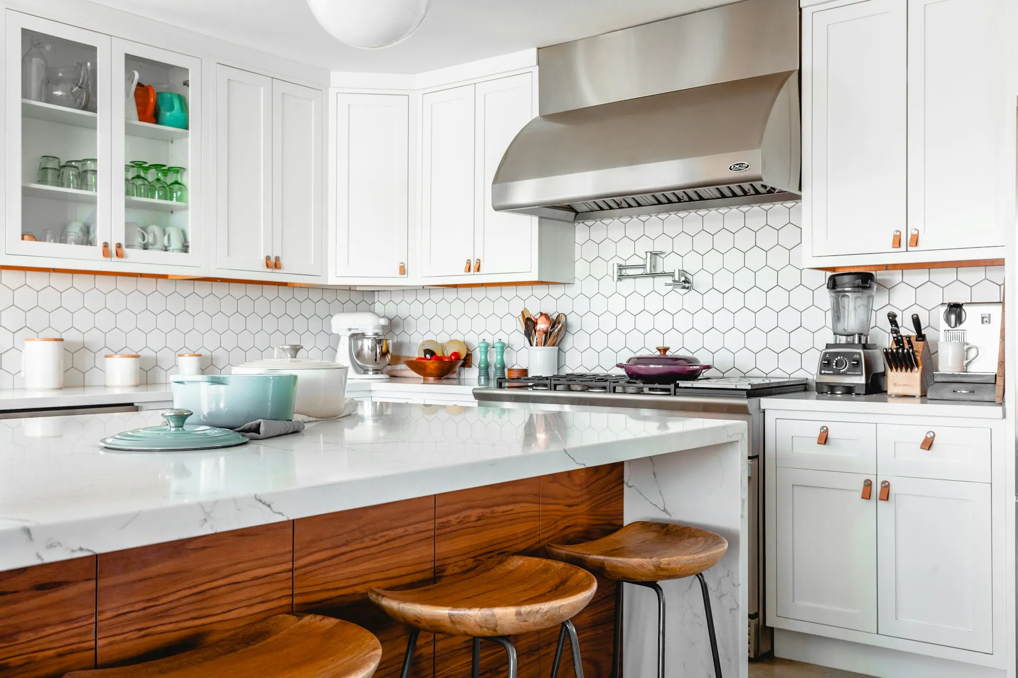 Kitchen with hexagon tile backsplash, white cabinets and a walnut island