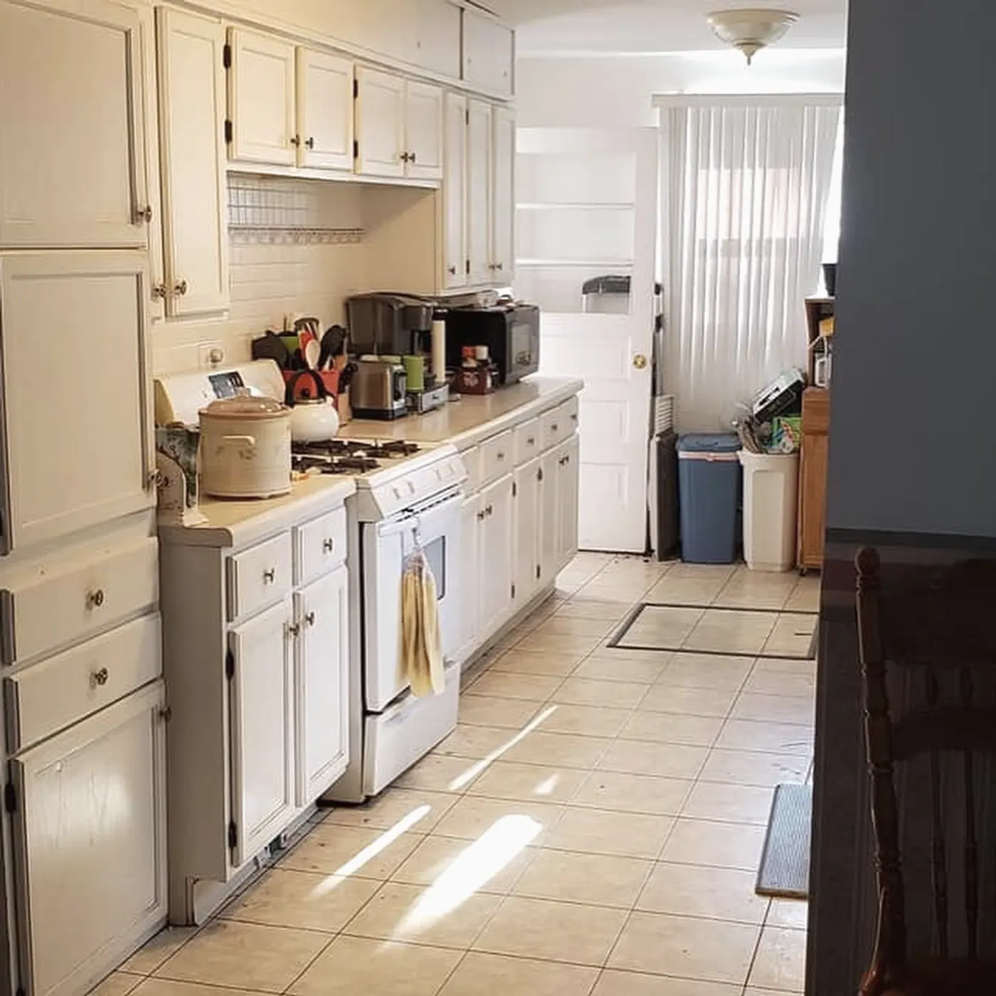 Before: galley kitchen with white cabinets, tile counters and a soffit