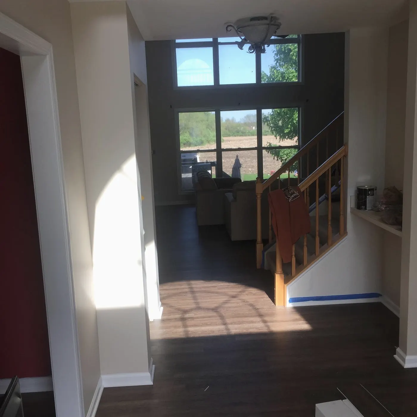 Entry hall and stairs with new plank flooring running toward a bright window
