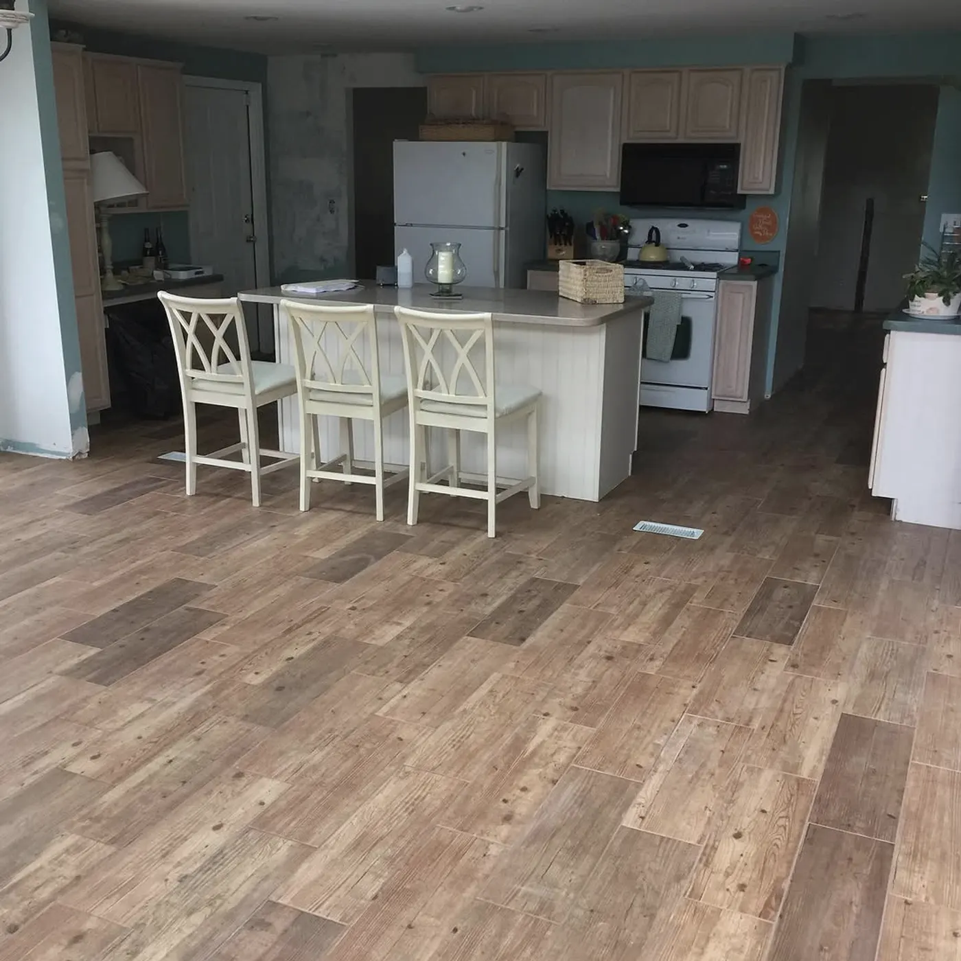 Kitchen with a white island and new wood-look plank flooring